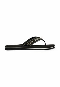 Sandalo flip-flop nero con una strap testurizzata che presenta la scritta "TOMMY HILFIGER" in lettere dorate, una suola piatta e una striscia di accento bianca sul bordo.