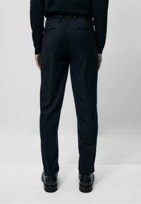 Marineblauwe broek met een ontspannen pasvorm, elastische tailleband en zijzakken. De stof heeft een gladde textuur; aan de achterkant bevinden zich twee onopvallende zakken.