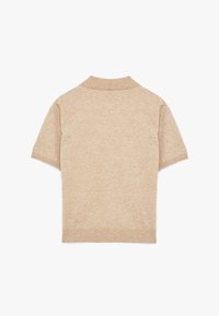 Beige kortärmad pikétröja med ribbad krage och nederkant. Tillverkad av ett mjukt, strukturerat tyg som visar en enhetlig färg. Inga mönster eller detaljer.