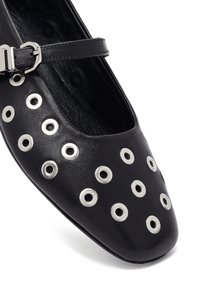 Ballet flat in pelle nera con punta arrotondata, dettagli con occhielli argentati e una sottile cinghia alla caviglia con fibbia argentata.