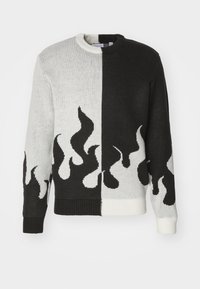 Gebreide trui met een gesplitst ontwerp; de ene helft zwart, de andere wit. Heeft vlammenpatronen in zwart en wit langs de zoom en mouwen.