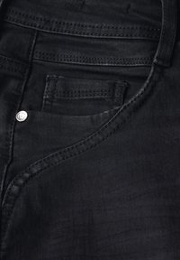 Tejido de mezclilla negra que presenta un bolsillo delantero con costura visible y un botón de metal. La textura es suave con un ligero brillo.