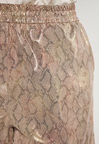 Metallic rosegouden broek met een gestructureerd slangenprintpatroon. Elastische tailleband met een gladde afwerking en reflecterende kwaliteit.