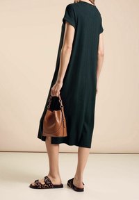 Vihreä raidallinen midimekko, jossa on kääntösateet, yhdistettynä ruskeaan käsilaukkuun ja leopardikuvioisiin liuku sandaaleihin. Sileä tekstuuri, rento malli.