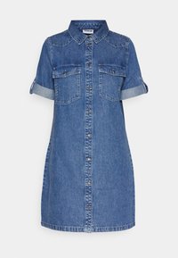 Jeanskjol med krage, korta uppvikta ärmar, två bröstfickor och knäppning fram. Har en blekt blå färg.