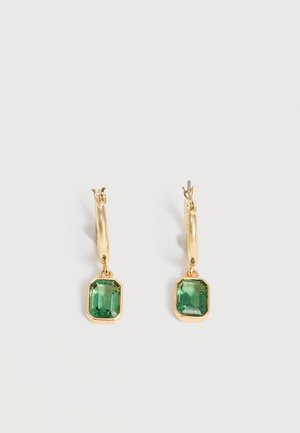 Χρυσά σκουλαρίκια κρίκοι με ορθογώνιες πράσινες πολύτιμες πέτρες κρεμασμένες από κάθε κρίκο, σε απλό φωτεινό φόντο.