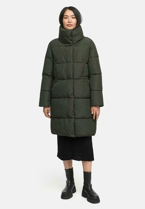 Puffer coat in dark green, featuring a high collar and quilted design. Paired with a black ribbed skirt and black chunky boots.