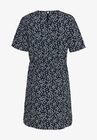 Krátké rukávy, námořnická modrá šaty s bílým květinovým vzorem, kulatým výstřihem a nařaseným pasem. Na zadní straně malé otvor ve tvaru klíče s knoflíkem.