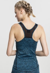 Top atletico senza maniche in blu heather con pannello posteriore in rete scura, design a spalla larga e cuciture piatte per il comfort. Tessuto testurizzato.