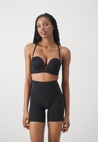Black seamless bra with a plunging neckline and thin straps, paired with high-waisted black shaping shorts. Smooth matte texture.