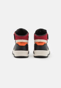 Une paire de baskets montantes Geox noires, rouges et orange vues de l'arrière sur un fond blanc.
