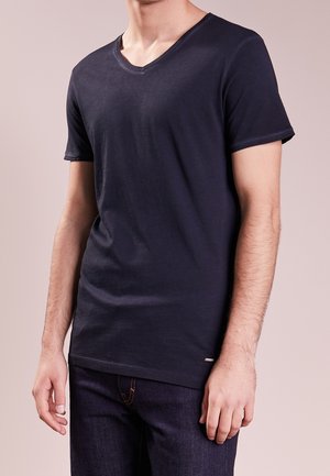 T-shirt in cotone blu navy con maniche corte e scollo a V. Presenta un orlo dritto e un discreto dettaglio del marchio vicino all'orlo inferiore.