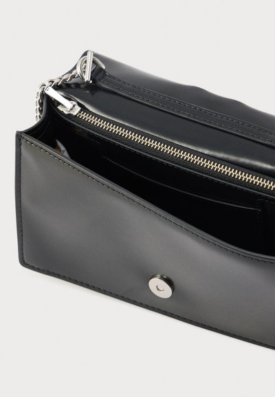 Zwarte clutch van kunstleer met een ritssluiting aan de bovenkant, zilverkleurige hardware, een gladde structuur en een drukknoopsluiting. Het interieur heeft vakken.