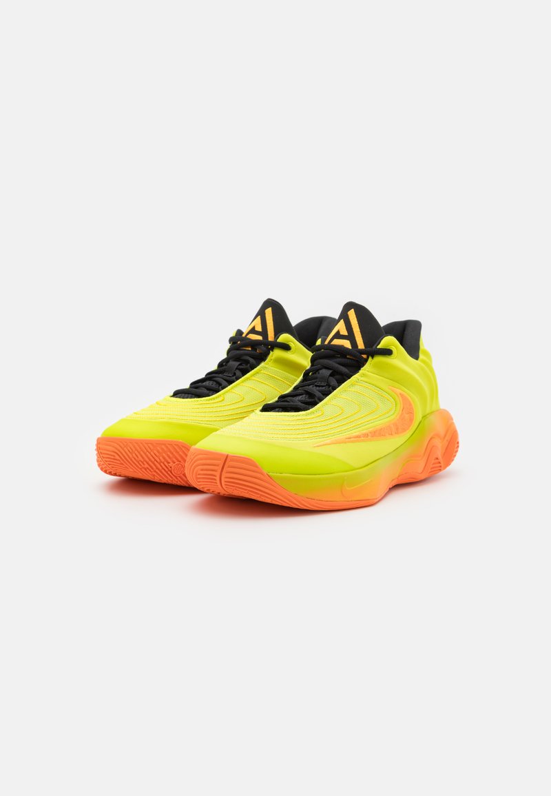 Scarpe da ginnastica verde lime con una suola intermedia arancione. Presentano una parte superiore texturizzata con lacci neri e dettagli del logo sulla linguetta.