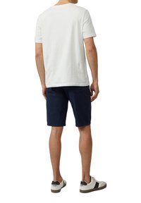 Biała bawełniana koszulka i granatowe spodenki, z kieszeniami, noszone z białymi i czarnymi trampkami. Casualowy design, standardowy krój.