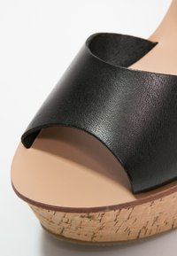 Sandale à glissière en cuir noir avec une large empeigne incurvée et une semelle plateforme en liège épaisse. Texture lisse avec une finition en liège naturel.