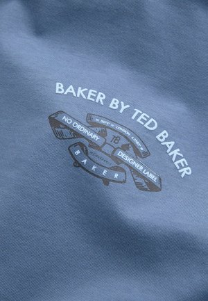 Harmaa kangas, jossa on sileä rakenne ja painettu logo: "BAKER BY TED BAKER" valkoisena ja tummanruskeana, lisättynä koriste-elementeillä.