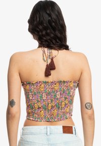 Multikleurige haltertop met een bloemenpatroon in roze, paars, geel en groen. Heeft franjes en is gemaakt van elastische, textuurstof.