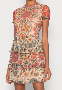 Robe à manches courtes avec un motif floral en rouge, bleu et crème, dotée de volants superposés et d'un corsage ajusté. Fabriquée en tissu léger.