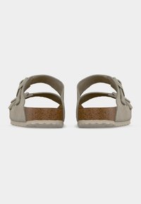 Ζευγάρι μπεζ σουέντ σανδάλια με ρυθμιζόμενες λουριά και πάτους από φελλό, σε προβολή από πίσω, σε λευκό φόντο.