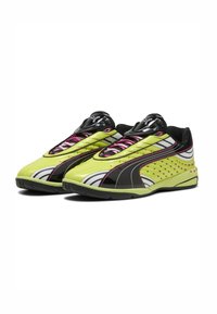 Scarpe da ginnastica gialle brillanti con un accento nero lucido, motivi bianchi, lacci rosa e texture a pois sui lati per ventilazione.
