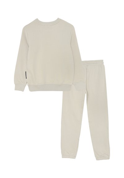 Completo di felpa a maniche lunghe color beige chiaro e pantaloni della tuta coordinati con vita elastica, posati su uno sfondo bianco.