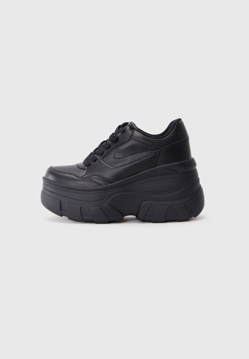 Baskets compensées en cuir noir avec une semelle épaisse et texturée, design à lacets, vues de côté sur un fond gris clair uni.