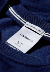 Marineblauer Strickpullover aus australischer Merinowolle, mit einem Etikett, auf dem "LINDERGH", "1927" und "PREMIUM" in kontrastierendem weißen Text steht.