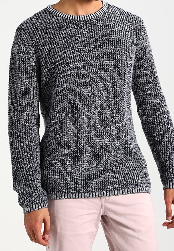 Grauer gestrickter Pullover mit strukturiertem Muster, rundem Ausschnitt und gerippten Bündchen. Getragen mit hellrosa Hosen.