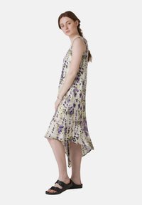 Rochie midi cu imprimeu floral din țesătură transparentă, cu un tiv asimetric, bretele ajustabile și modele multicolore în nuanțe de violet și verde.