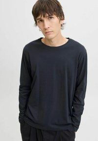 Zwarte T-shirt met lange mouwen, gemaakt van lichtgewicht stof, met een ronde halslijn en een relaxed pasvorm met subtiele draping.