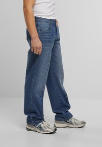 Lyseblå denimjeans med rett passform, fem-lomme-design og subtil fading, kombinert med sølvfargede joggesko.
