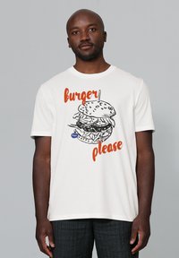 T-shirt blanc à manches courtes présentant un graphisme d'un hamburger avec le texte "burger s'il vous plaît" en orange. Coupe décontractée, en coton.