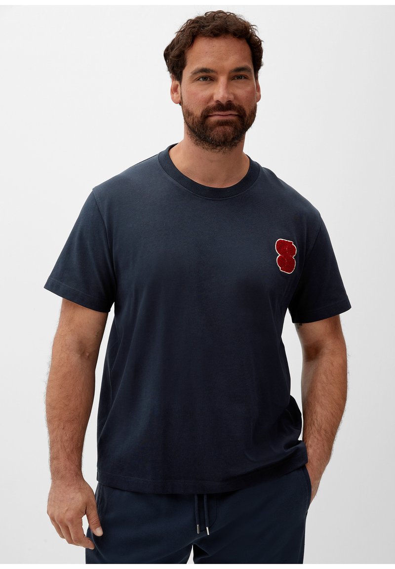 Dunkelblauses Baumwoll-T-Shirt mit Rundhalsausschnitt und kurzen Ärmeln, mit einem roten, gestickten Bärenmotiv auf der linken Brust.