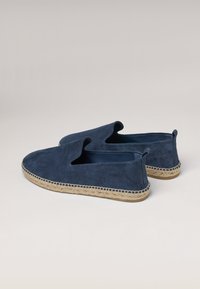 Zapatos sin cordones de ante azul marino con suela de yute trenzada, presentan un corte alto y un empeine abierto para un diseño relajado y un contraste de texturas.