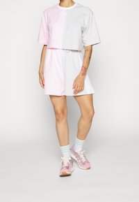 Dvoudílný outfit skládající se z krátkého šedého a růžového triku s barevným blokováním a odpovídající sukně ke kolenům s nastavitelným pasem.