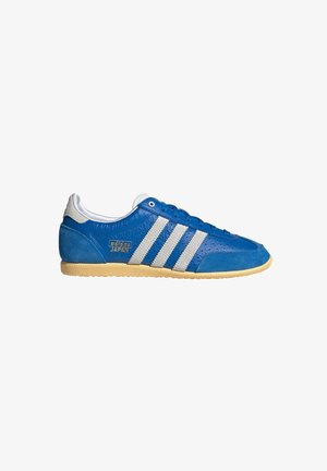 Zapatillas de ante y cuero azul con tres rayas blancas, detalles perforados, una suela de goma amarilla y un pequeño logo dorado.