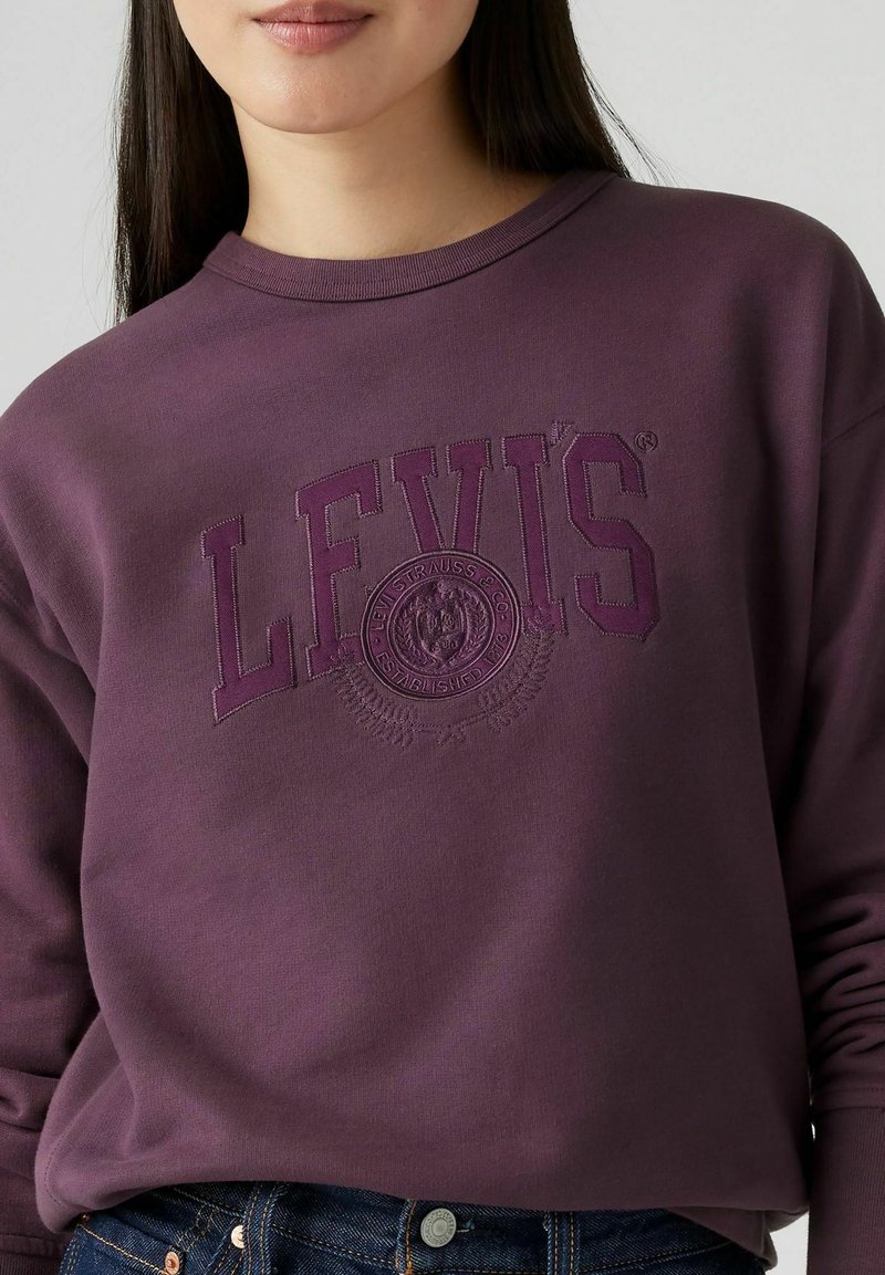 Lila Sweatshirt mit geprägt "LEVI'S" Logo und kreisförmigen Details. Verfügt über einen runden Halsausschnitt und lange Ärmel, aus weichem Stoff gefertigt.