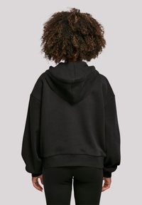 Black oversized hoodie with a hood, dropped shoulders, ribbed hem, and cuffs. Soft, textured fabric provides warmth and comfort.