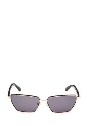 Gafas de sol hexagonales con lentes oscuros, acentos de metal dorado y brazos de plástico negro. Presenta un diseño texturizado a lo largo del borde superior.