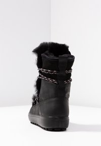 Botte d;cheville imperm;able noire avec une tige textur;e, une bordure en fourrure et des lacets tress;s. Caract;ristiques d'une semelle en caoutchouc robuste et d'un talon moul;e pour un soutien optimal.