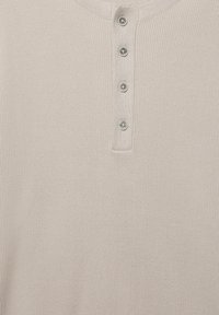 Vaaleanbeige neulottu paita pyöreällä pääntiellä ja edessä pystysuuntainen rivi, jossa on neljä pientä, pyöreää, vaaleaa nappia.