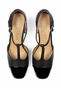 Scarpe con tacco alto nere con punta lucida nera, parte superiore in pelle e design a T-strap con fibbia regolabile.