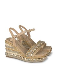 Sandales compensées beiges avec des brides en corde tressée et ornées, dotées d'une semelle plate et de strass décoratifs sur la semelle.