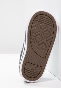 Brązowa gumowa podeszwa sneakersa z geometrycznym wzorem, z białymi krawędziami oraz granatowym płóciennym wierzchem z czarnymi akcentami linii.