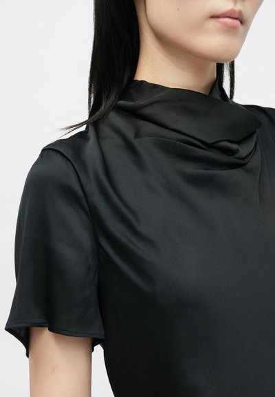 Mustalüheline, lühikeste varrukatega topp sujuvast, kergest kangast, millel on langev dekoltee. Omab peent läiget ja väljakujunenud lõiget.