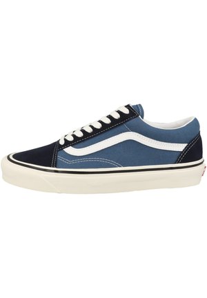Blue and navy canvas sneaker with white accents, black sole detailing, and flat white laces. Features a classic low-top design and stitching details.