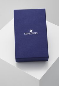 Swarovski gaveboks, rektangulær, teksturert mørkeblått materiale, med en hvit logo av en svane og merkenavn på forsiden.