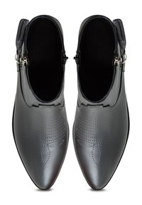 Botas de tobillo de cuero gris con puntas afiladas, que presentan detalles de costura y acentos de cremallera de hardware plateado. Textura suave, diseño minimalista.
