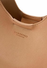 Borsa in pelle marrone chiaro con texture liscia, dotata di un'apertura arrotondata e logo del brand impresso. Dettagli di cucitura sottili lungo il bordo.